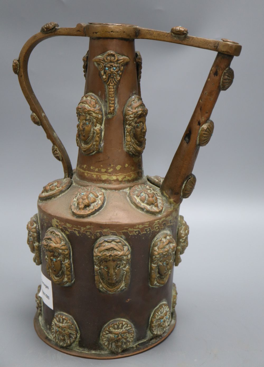 A Middle Eastern copper pot, decorated with classical ladies and lions faces with turquoise beaded eyes, height 32cm